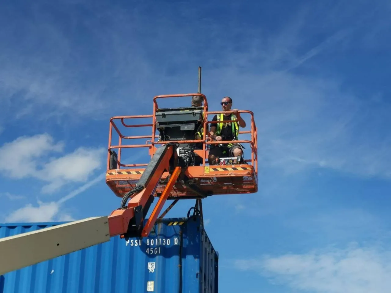 Working from a cherry picker on site at DRYSTACK, against a blue sky